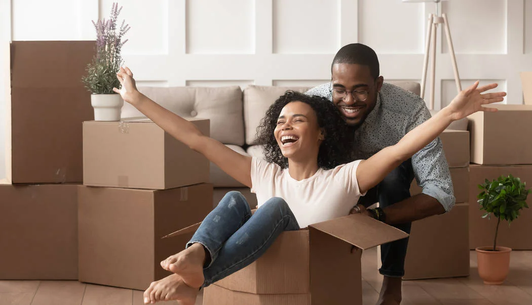 A couple having fun with moving boxes in a new home.